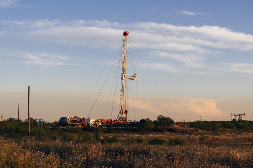 Drilling rig in West Texas prairie grasses with pumpjacks in the background