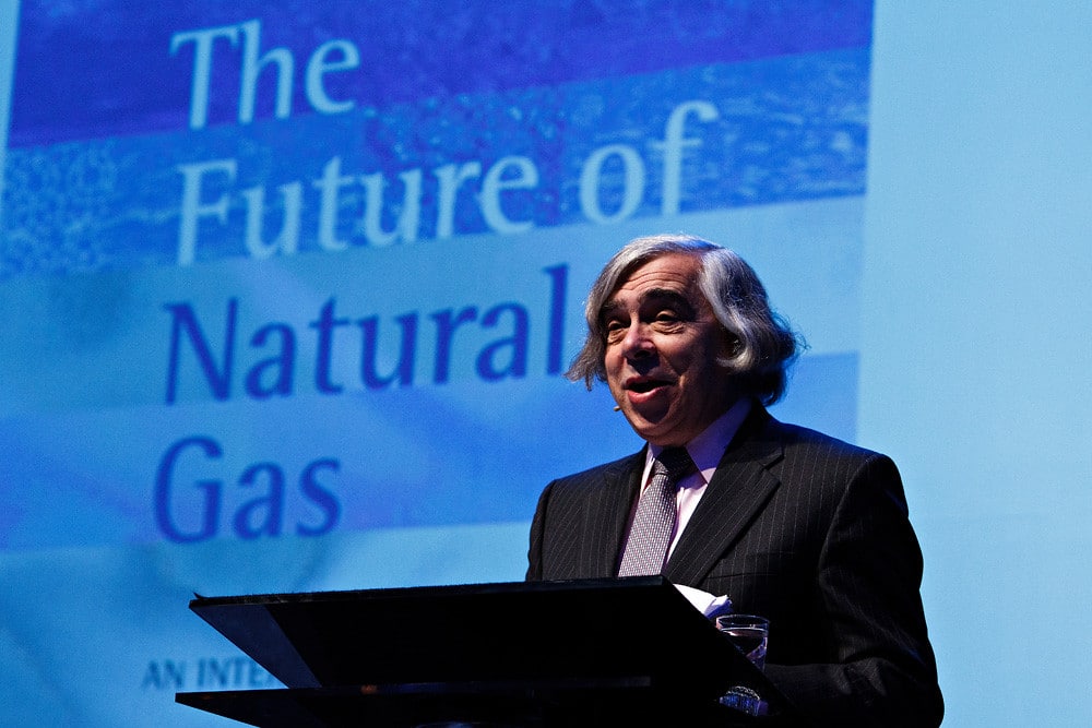 Ernest Moniz standing at a podium with "The Future of Natural Gas" on a blue background projected behind him.