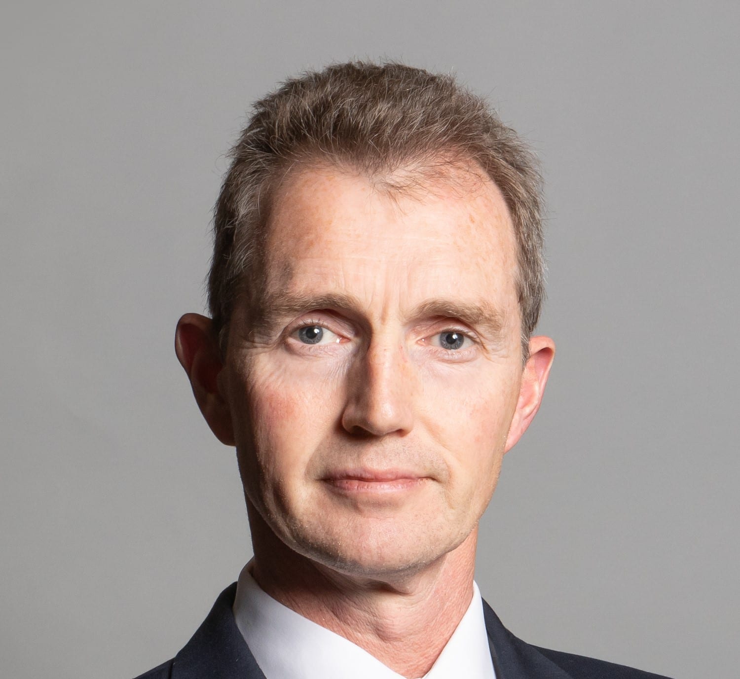 a headshot of a white man with gray hair in a suit