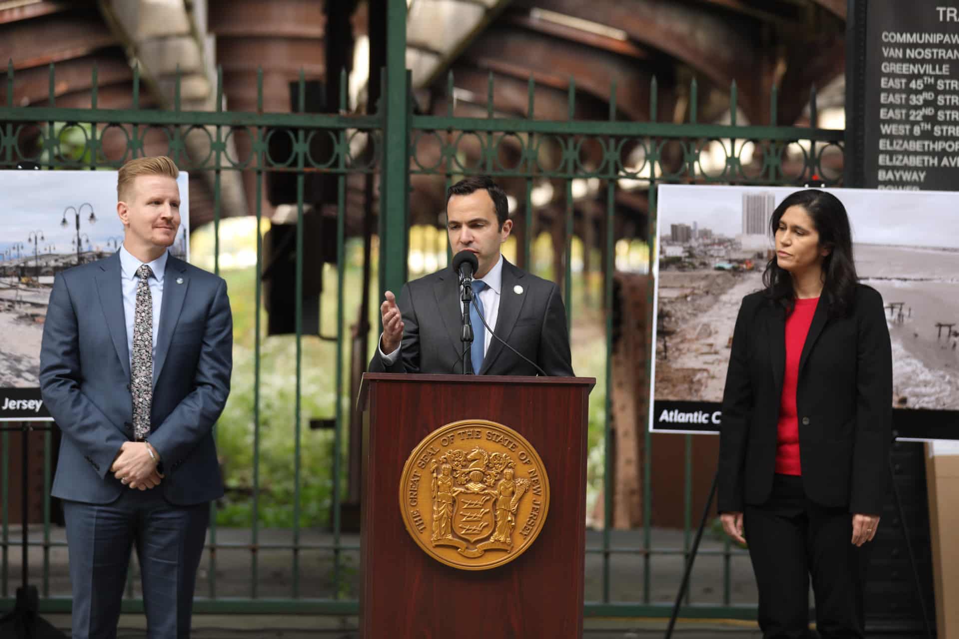 Two men and a woman stand at a press conference