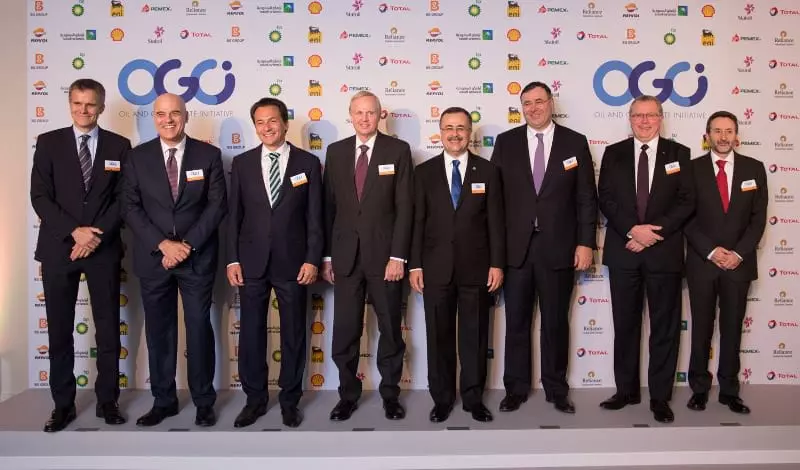Eight men in suits and ties stand on a stage in front of a background of oil company logos and 'Oil and Gas Climate Initiative'