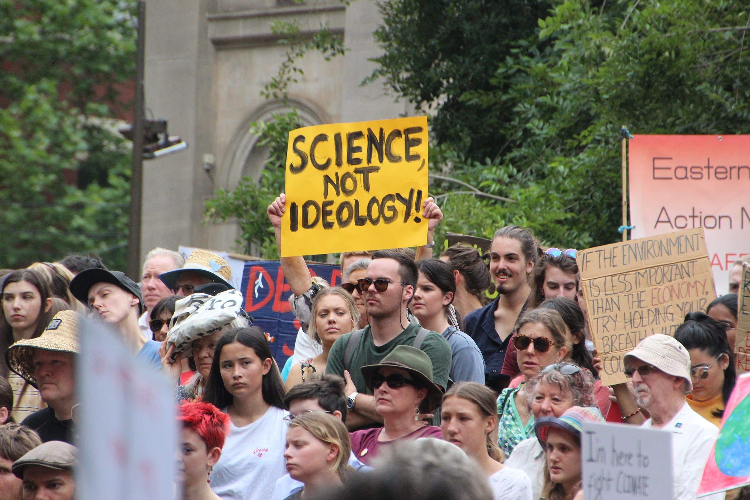 a protester holds a yellow sign that says "science is not ideology!"