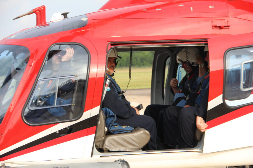 Crew sits inside a red and white helicopter still on the ground