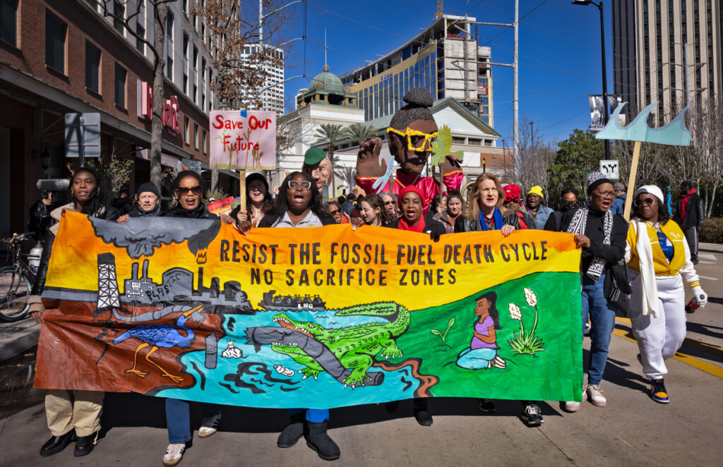 A protest march of environmental groups opposed to permitting more LNG export facilities, carrying a colorful painted banner through the streets of New Orleans.