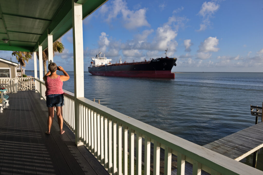 A woman on a deck photographs an LNG tanker en route to Corpus Christi LNG