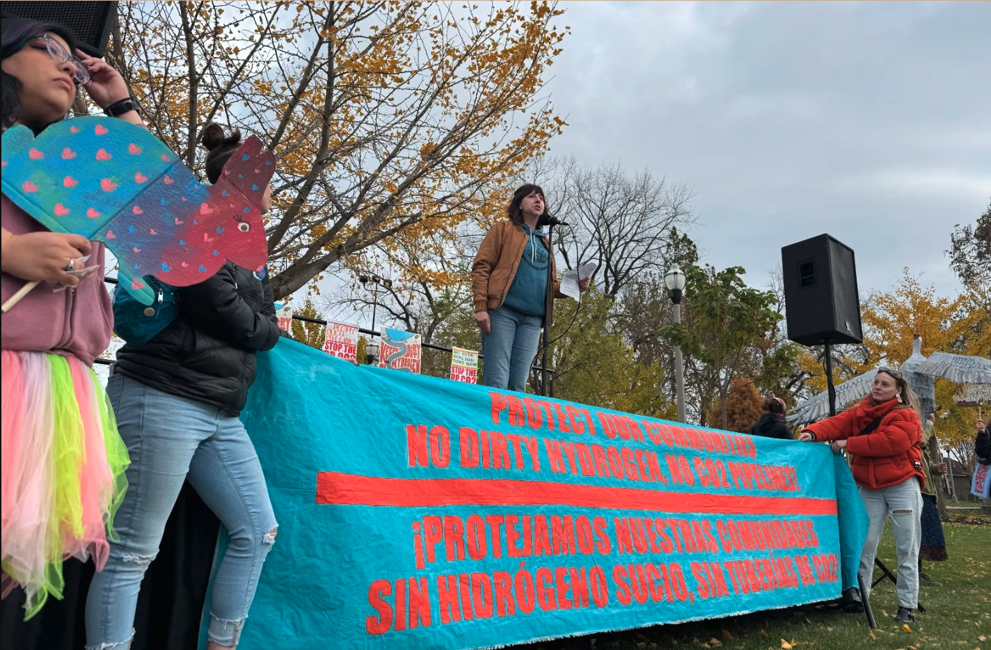 Activists holding a banner that reads: protect our communities. no dirty hydrogen, no CO2 pipeline, in English and Spanish.